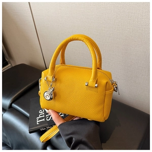 Détail du sac Boston en cuir grainé jaune avec breloque sphère argentée et bandoulière