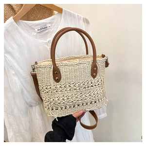 Detailed view of handmade woven straw bag featuring brown leather handles and drawstring liner