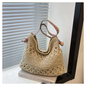 Detail of hollow floral straw tote bag with colorful geometric woven shoulder strap