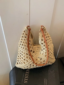 Minimalist cream straw woven tote bag with brown leather straps on a black bench