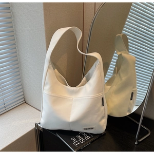 Detail of white nylon tote bag showing MEAREY logo patch and external pocket design