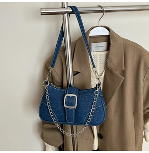 Detail of blue denim shoulder bag with silver buckle and chain on fashion background
