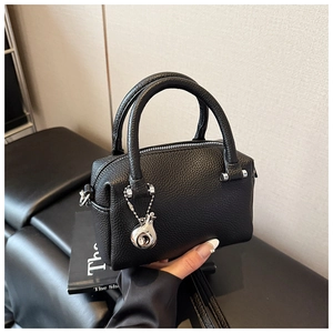 Vue détaillée du sac Boston en cuir noir avec ferrures argentées et pendentif élégant