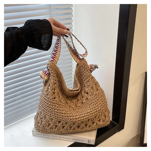 Detail of hand-woven straw tote bag with floral patterns and a colorful ethnic shoulder strap