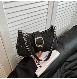 Detail showing black denim fabric texture with white contrast stitching and silver buckle
