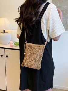 Chic hand-woven straw bucket bag with floral cutouts and tassel details for summer