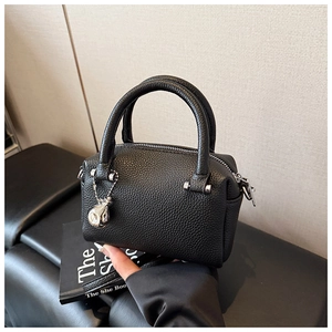 Détail du sac Boston noir avec grain litchi, fermeture éclair et pendentif argenté