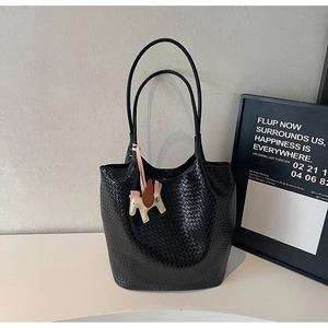 Close-up of black woven texture tote bag with a colorful horse charm accessory