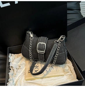 Detail of black denim saddle bag with silver buckle and chain in elegant gift box