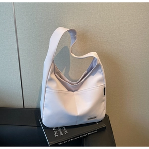 Close-up of hobo bag showing side brand tag and front pocket on leather surface