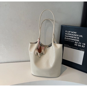 Detailed close-up of woven cream tote bag texture with decorative horse charm