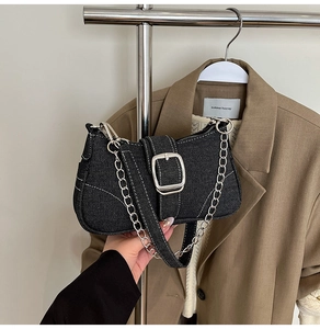 Detail of dark denim crossbody bag with contrast stitching and silver metal buckle