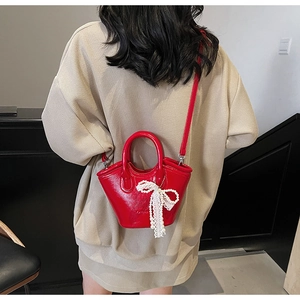 Detail of red patent leather mini bucket bag with white lace pearl bow pendant charm