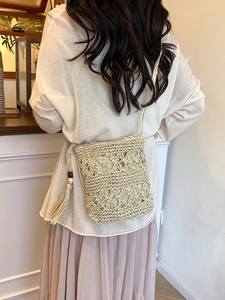 Beige handcrafted woven bucket bag with fringe tassels and delicate hollow flower pattern
