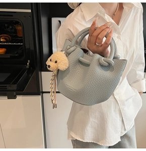 Detail of light blue lychee pattern handbag with a brown poodle plush charm