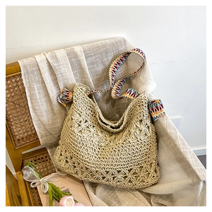 Detail of hand-woven straw tote with hollow floral patterns and colorful boho strap