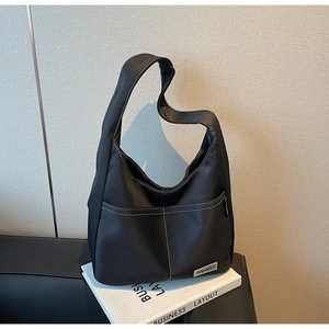 Close-up of black nylon shoulder bag with contrast white stitching and brand label