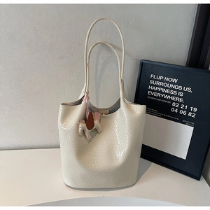 Detail of cream white woven bucket bag featuring a decorative pony charm on a white surface
