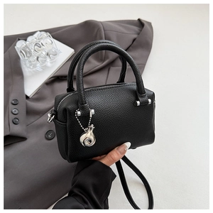 Détail du sac à main en cuir noir à motif litchi avec accessoires en argent poli