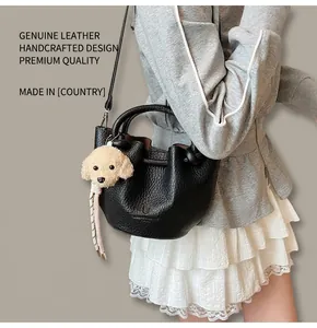 Détail du sac seau noir en cuir grainé avec un pendentif peluche en forme de chien mignon