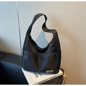 Detail of black tote bag with white contrast stitching and spacious front pocket