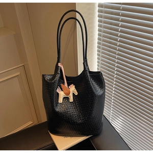 Detail of black woven tote bag featuring a leather Pegasus charm and large bucket capacity