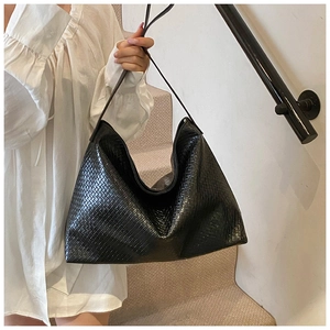 Close-up of a black woven Hobo shoulder bag with fine texture held on a staircase