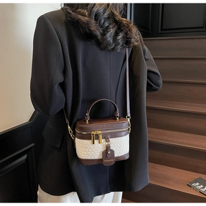 Detail of a mini bucket bag featuring beige woven fabric and dark brown leather trim