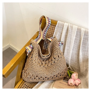 Detail of woven straw bag showing hollow floral patterns and colorful jacquard strap