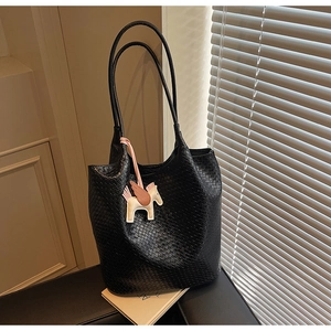 Detail of black woven texture tote bag with a decorative leather horse charm accessory
