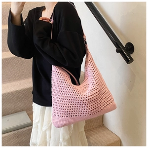 Close-up of pink crochet knit beach bag with hollow mesh texture on a stylish model