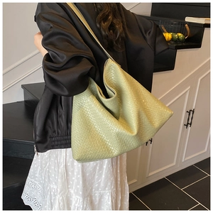 Detailed close-up of large light green woven leather tote bag with intricate texture