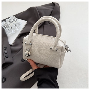 Détail du sac Boston en cuir grainé blanc cassé avec pendentif en métal argenté élégant