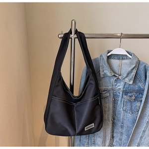 Close-up of black nylon hobo bag with white stitching and Mearey brand logo tag