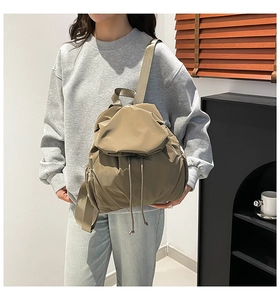 Detail of khaki waterproof nylon backpack with drawstring closure and flap on model