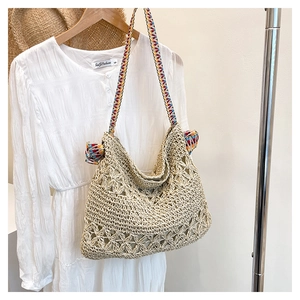 Detail of bohemian straw tote bag with crochet flower patterns and colorful bow