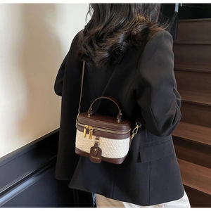 Rear view of a model carrying the two-tone PU leather bucket bag on a modern staircase