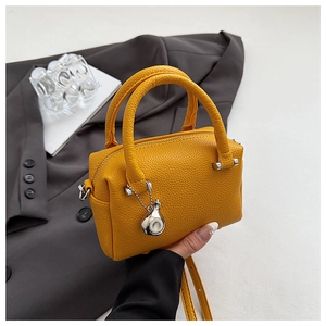 Détail du sac Boston en cuir litchi jaune vif avec breloque argentée et doubles poignées