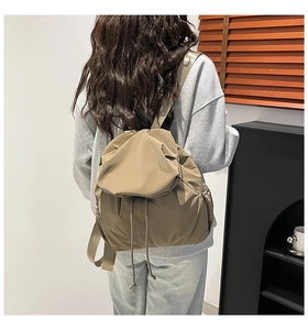 Detailed back view of a khaki pleated backpack showing the nylon fabric and shoulder straps