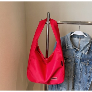Detail of red Hobo tote bag showing the rubber brand tag and functional side pocket