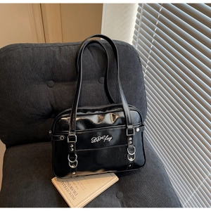 Close-up of black glossy shoulder bag with white embroidery and metallic silver hardware