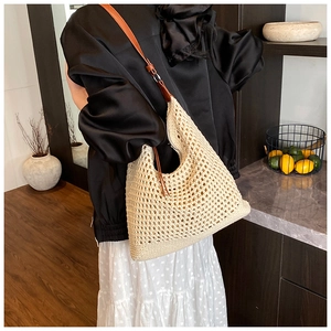 Detail of hand-woven cream beach bag featuring premium brown leather strap on shoulder