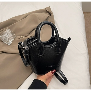Close-up of glossy black high-shine handbag featuring silver metal hardware and fine texture