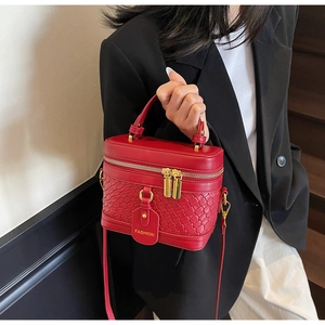 Detail of red croc-embossed structured handbag with gold zipper and fashion tag
