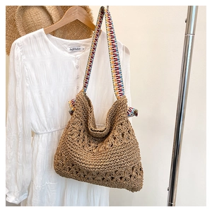 Detail of hand-woven straw tote bag featuring ethnic colorful strap and hollow pattern