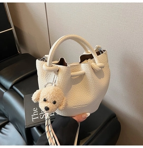 Détail du sac seau blanc crème avec motif litchi et breloque chiot en peluche