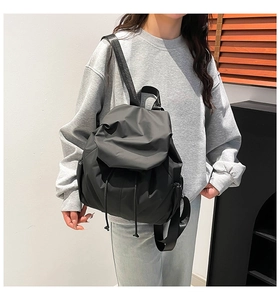 Detail of minimalist black nylon drawstring backpack showing pleated fabric and side zipper