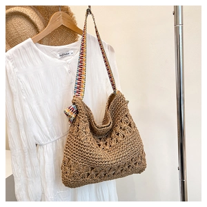 Detail of hand-woven straw tote with hollow floral patterns and ethnic colorful strap