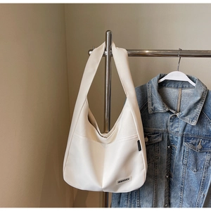 Close-up of a white minimalist shoulder bag hung on a hanger with a denim jacket