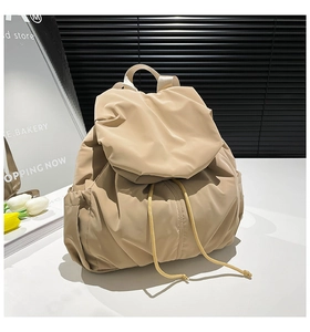 Detail of beige pleated nylon backpack featuring drawstring closure and side storage pocket